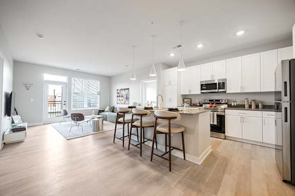 A modern kitchen with a bar stool and a dining table.